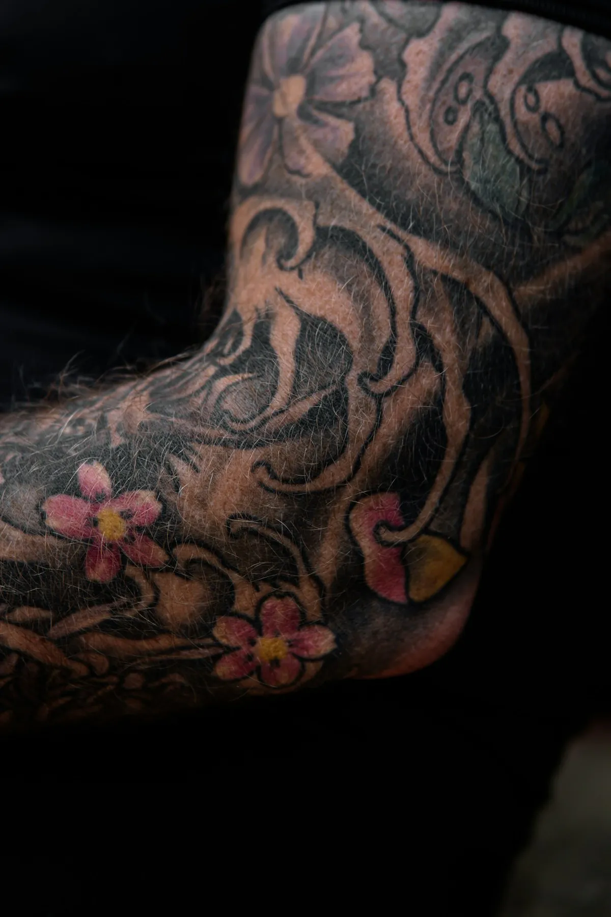 Gomito tatuato con fiori di ciliegio e acqua in stile giapponese
