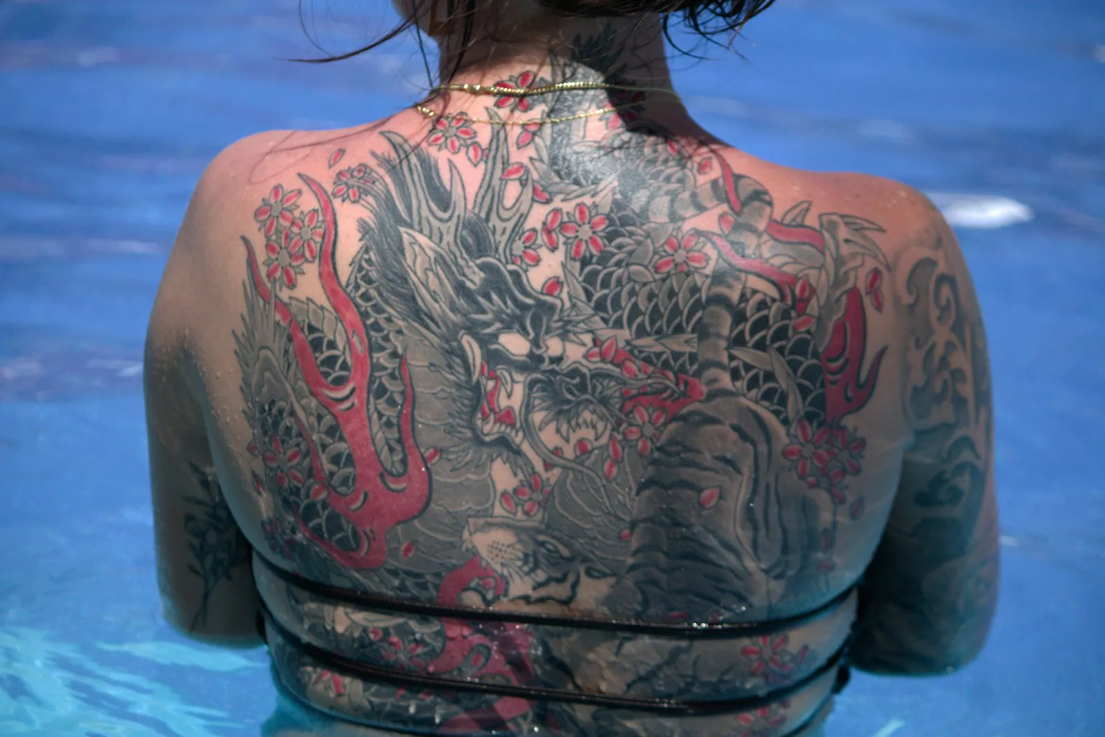 Schiena di donna con drago giapponese a colori, in piscina