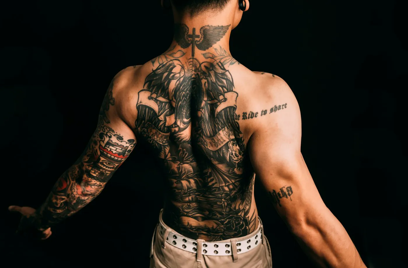 Uomo di spalle con schiena e braccio completamente tatuati